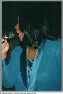 Photograph of a woman singing into a microphone