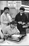 [Three African American women at a polling place, one looking at a book of registered voters on November 5, 1957, in New York City or Newark, New Jersey]