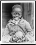 [African American boy holding a piece of fruit received through the Red Cross drought relief work in Mississippi]