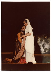 Performance photo of a man and a woman embracing, the woman is wearing white]. [color photoprint