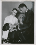 United States Navy dentist Lt. Frank Louis Peterson, Jr. (right) with an unidentified assistant, performing a dental examination