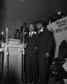 Martin Luther King Jr. at the podium with another man, possibly Reverend Nelson H. Smith Jr., at the annual Men's Day celebration at New Pilgrim Baptist Church in Birmingham, Alabama.