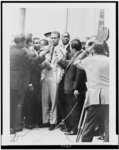 [Malcolm X, full-length portrait, standing, facing slightly left, being interviewed by reporters]