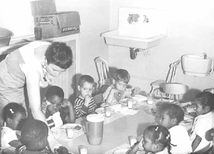 Evelyn House with children at lunch time, Hallie Q. Brown nursery school, St. Paul.