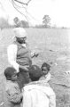 Wife and children of John Nixon standing in their yard in Autaugaville, Alabama, looking at photographs of themselves.