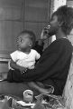 Young woman holding a baby while sitting on the porch of a house in Little Korea, a neighborhood in Birmingham, Alabama.