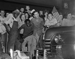 Crowd of people celebrating V-J Day on a sidewalk in downtown Birmingham, Alabama.