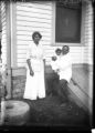 Photograph of an unknown young family, in front of a house, undated