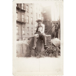 Unidentified man perches on wall with a cigarette