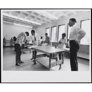 Roxbury Boys' Club members working on projects for their woodworking class while the Club director Roscoe Baker, at far right, looks on