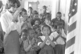 Teacher and students saying a prayer in a classroom.