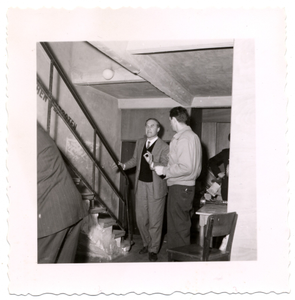 Norman Granz talking to another man near staircase, undated.] [Black-and-white photoprint