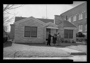 Photograph of Three People in Front of a House