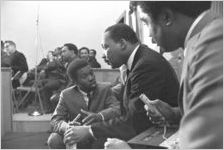 Thumbnail for Martin Luther King, Jr., seated and speaking to a young man during a meeting at Maggie Street Baptist Church in Montgomery, Alabama.