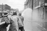 Firemen spraying adolescent civil rights demonstrators with a hose during the Children's Crusade in downtown Birmingham, Alabama.