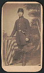 [Soldier named Lee Wilson in Union uniform with sword and American flag in front of painted backdrop showing trees and flag in background]