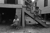 Little boy and girl sitting in front of a wooden house on Clayton Alley in Montgomery, Alabama.