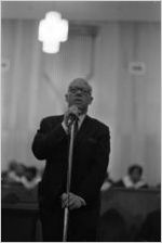 Rev. Jesse Douglas standing at a microphone at Holt Street Baptist Church in Montgomery, Alabama.