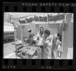 Samuel Bassey serving barbecued chicken to Joan Murray at booth in Leimert Park in Los Angeles, Calif., 1984