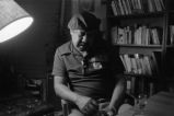 Gaines seated talking in front of bookshelves (EGP-9 #292)