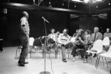 Etheridge Knight: Oxford, Miss. Knight performing at microphone in front of small audience (EKP 2-79-12/11 #295)