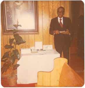 Chromogenic print of a man in a corner behind a church pew