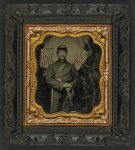 [Unidentified soldier in Union uniform with shoulder scales with pearl-handled revolver and saber in front of backdrop showing trees and two Great Star flags]