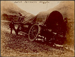 Two Boer Men, Farmers, and Two Black Men, with Covered Wagon Stuck in Mud in Mountains n.d