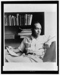 [Ralph Ellison , half-length portrait, seated holding glasses in one hand and a pencil and paper in the other]