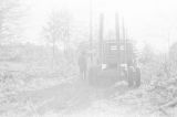 Man standing by a log truck near Mendenhall, Mississippi.