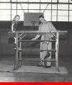 Young man helping two children performing gymnastics