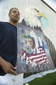 Lorenzo Green standing in front of a patriotic mural he is painting on the side of Lambert's Cafe on Highway 59 in Foley, Alabama.