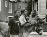 Two men walk with a donkey