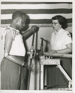 Occupational therapist instructing man on how to use his artificial arm for heavy duty work