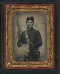 [Unidentified young soldier in Union uniform and Company D forage cap with handgun and cartridge box in front of painted backdrop showing military camp]