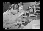 Production. Aircraft engines. Negro women with no previous industrial experience are reconditioning used spark plugs in a large Midwest airplane plant. Despite their lack of technical knowlege, these women have become expert operators of the small testing machines. Melrose Park, Buick plant