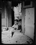 Washington, D.C. Three children waiting in the kitchen while their mother prepares the evening meal