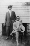 Men pose for photo beside a house