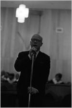 Rev. Jesse Douglas standing at a microphone at Holt Street Baptist Church in Montgomery, Alabama.