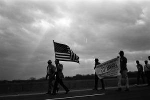 Man carrying an American flag during the 20th anniversary reenactment of the Selma to Montgomery March.