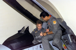 A US Air Force member (Right) of the 56th Fighter Wing's Egress Team, Luke Air Force Base, Arizona, assists US Congressman Matt Salmon, Representative of Arizona's 1ST District, in a simulator as he gets the proper training before his upcoming F-16 Falcon flight
