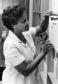 A nurse pulls a journal off the shelf in the library, circa 1985