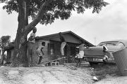 Angelina Foster and Robert Harris playing on a make-shift seesaw in the dirt yard in front of a brick house in Newtown, a neighborhood in Montgomery, Alabama.