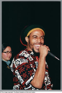 Photograph of a man smiling as he holds up microphone