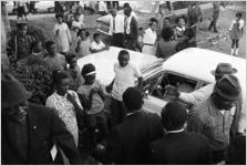 Martin Luther King, Jr., William M. Branch, Ralph Abernathy, and others, greeting a small crowd of people while walking toward a building, probably First Baptist Church in Eutaw, Alabama