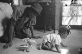 Percy Jones, Jr., kneeling on the floor with his daughter Barbara beside a bed in his home on Clayton Alley in Montgomery, Alabama.