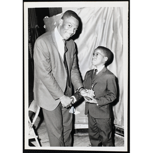 "Mr. Ralph Hilton, V.P. of the Kiwanis Club of Roxbury, presents Kiwanis trophies to the captains of the winning teams in the Roxbury Clubhouse, Boys' Clubs of Boston International Basketball Tournament"