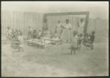 African-American children and women outside playing and eating at day nursery or play school