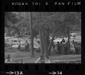 Reporters and photographers standing along fence bordering Black student rally in Franklin Park