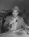 African-American man smiling for the camera with a drink in hand at a bar, Seattle, ca. 1950's